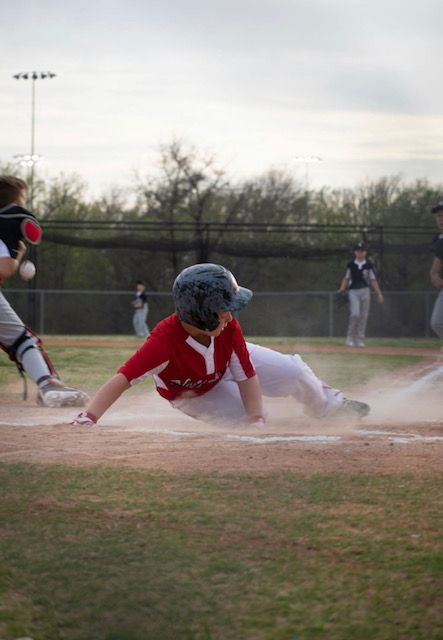 Dramatic sequence of a baserunner diving and sliding into base during a baseball game.