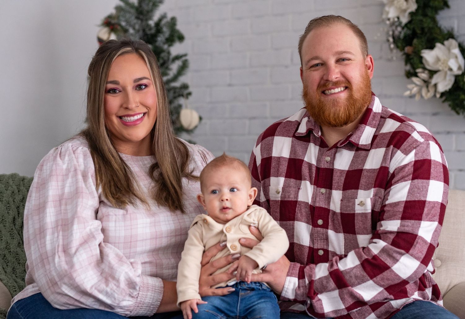 Family shares happy moments in matching buffalo plaid and pink outfits during outdoor photo session.