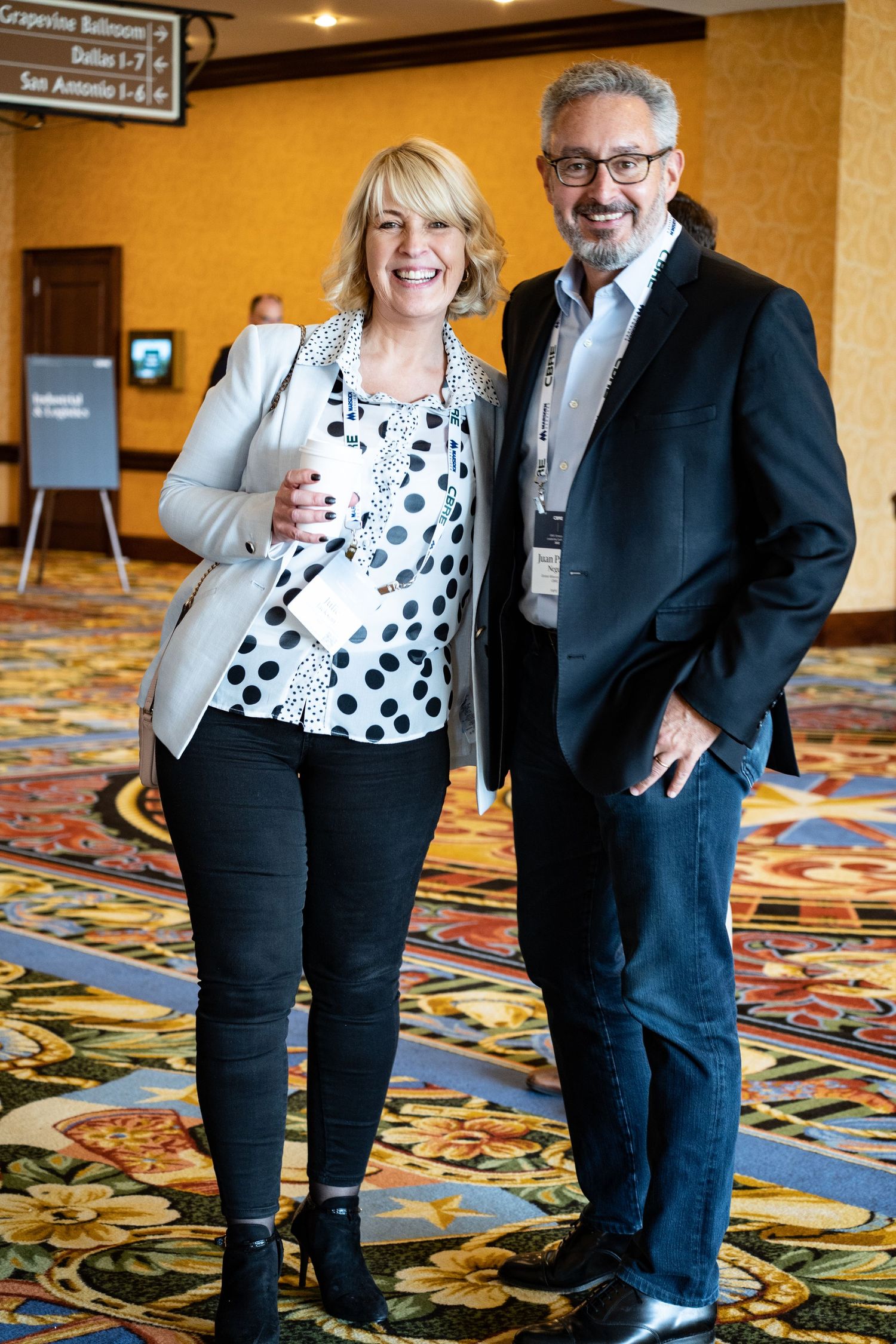 Conference attendees in business attire posing in front of event signage.