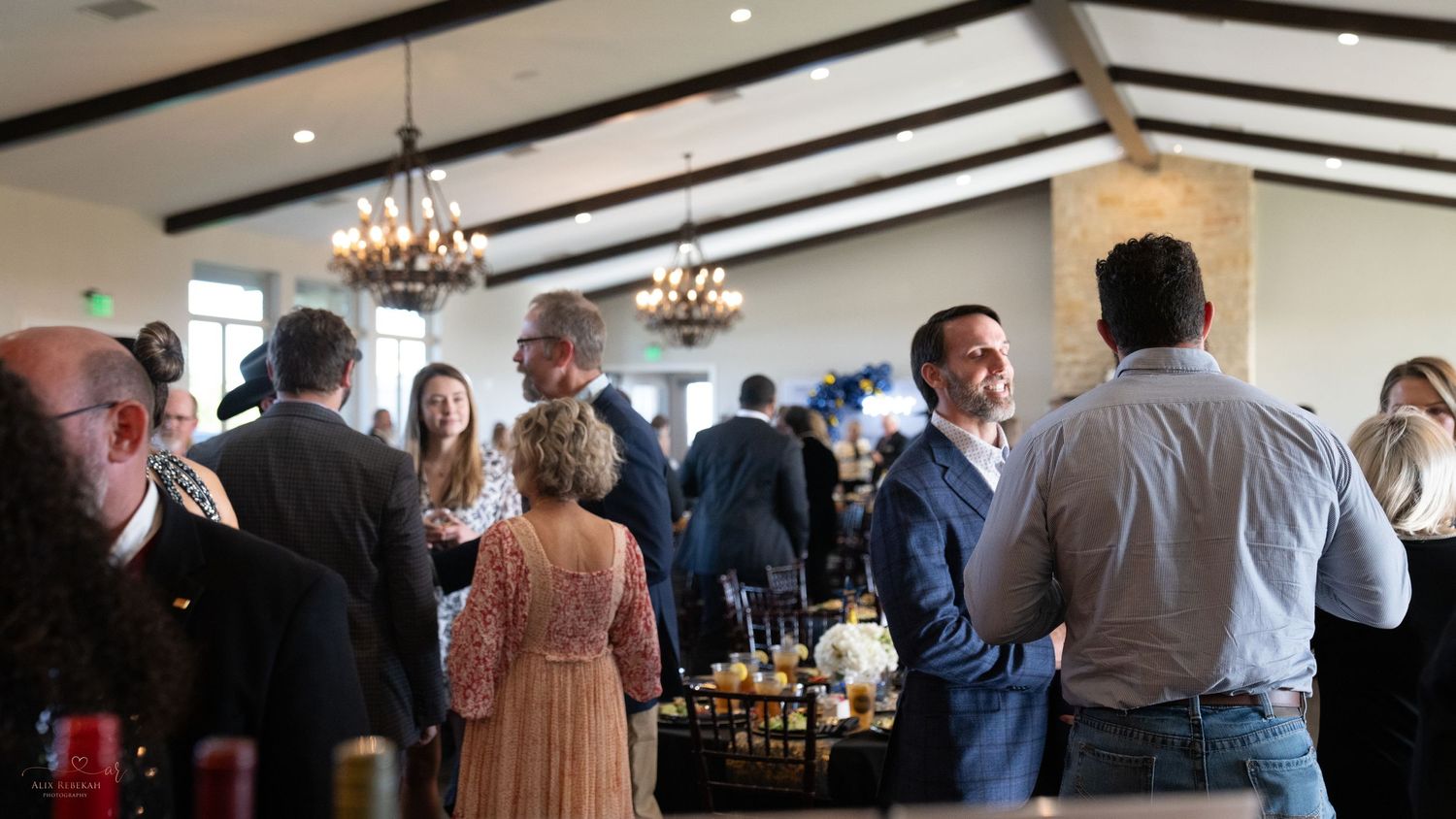 Guests mingling at formal evening reception under chandeliers.