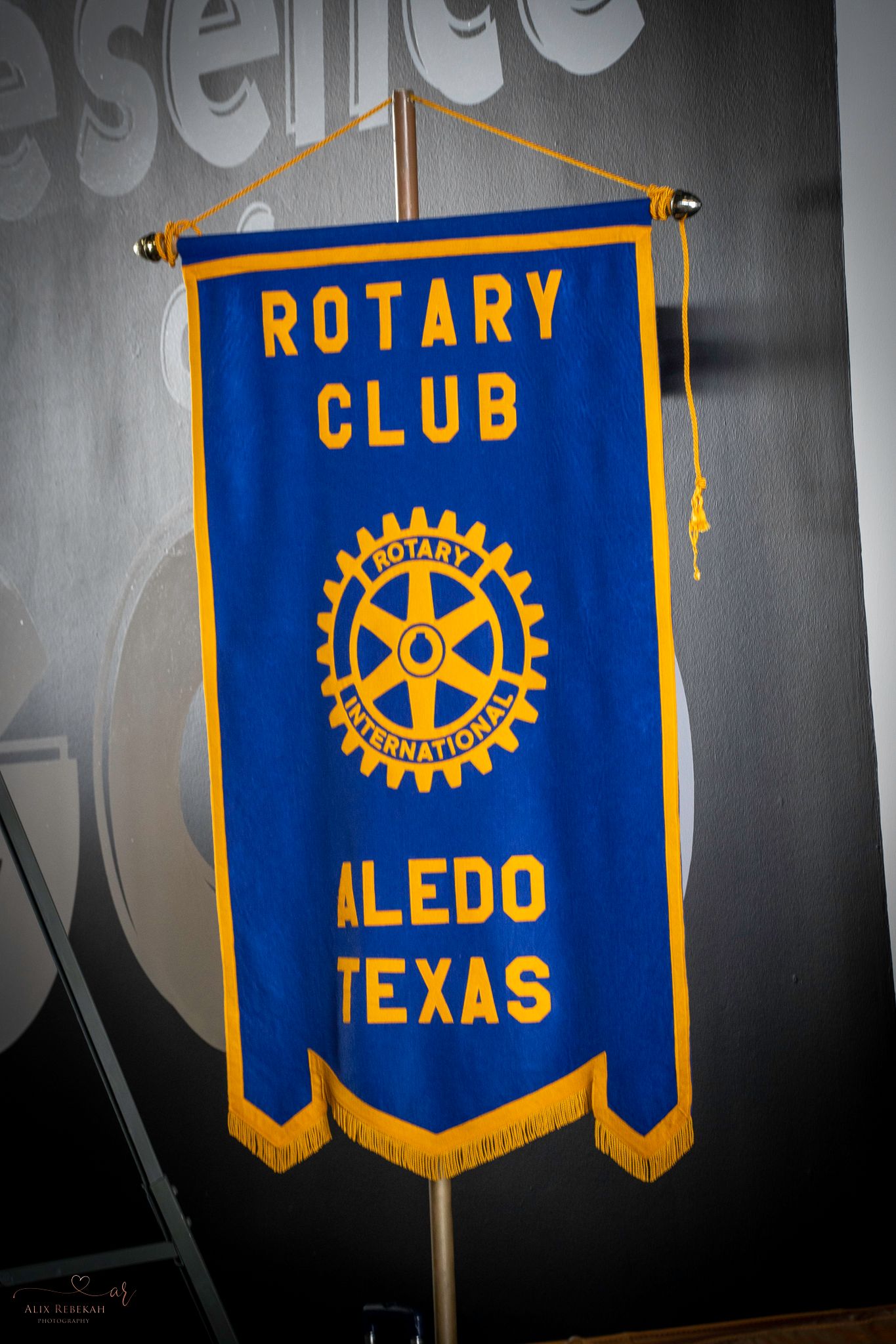 Blue and gold Rotary Club banner for Aledo Texas chapter displayed against dark background.