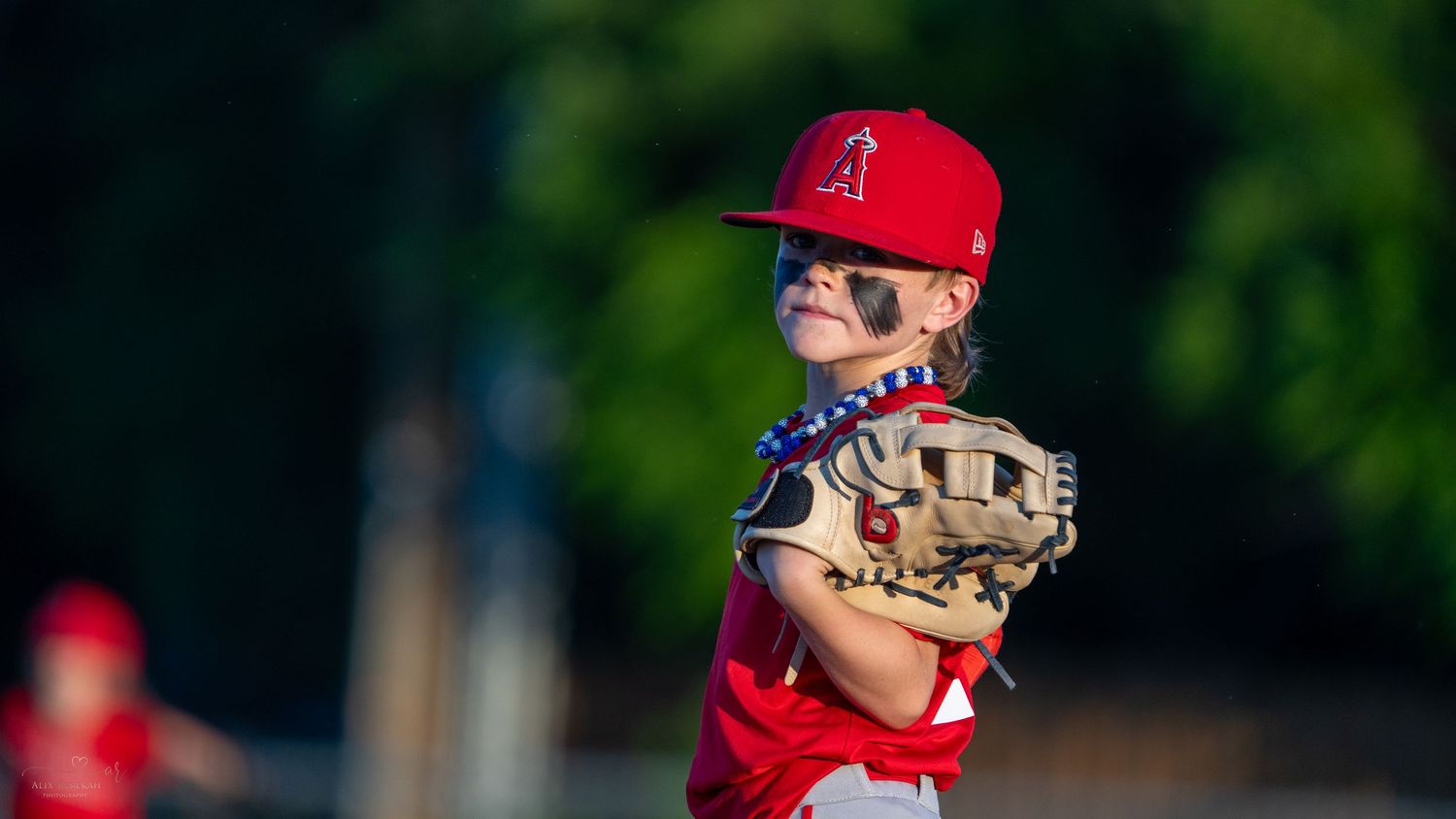 Young baseball player in red uniform ready to catch with mitt.