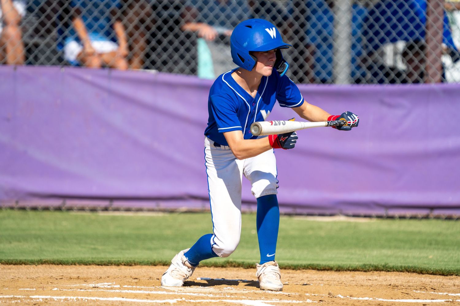 Baseball player in blue uniform prepares to bunt during game.
