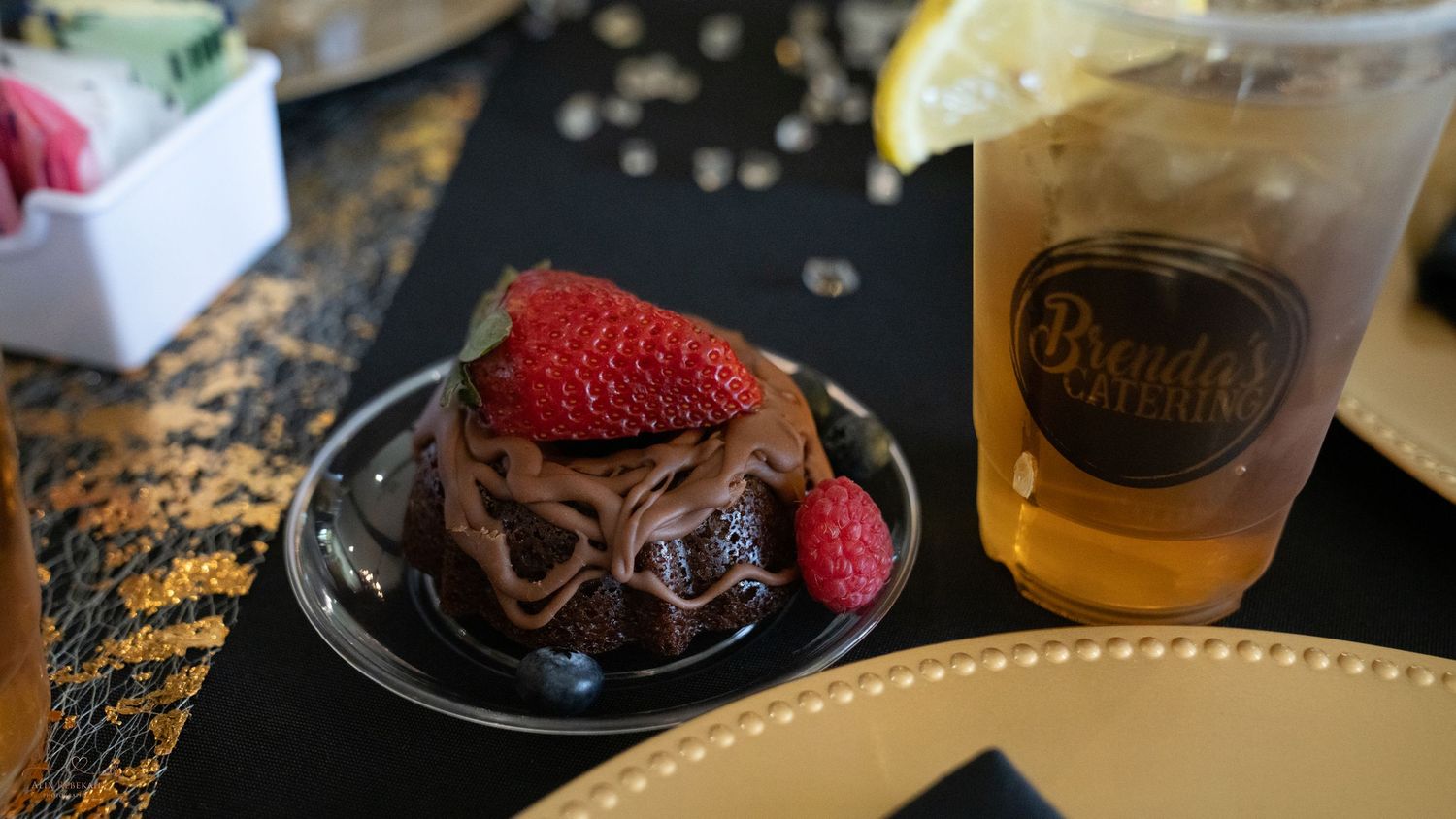 Chocolate dessert garnished with fresh raspberries served alongside craft beverage.