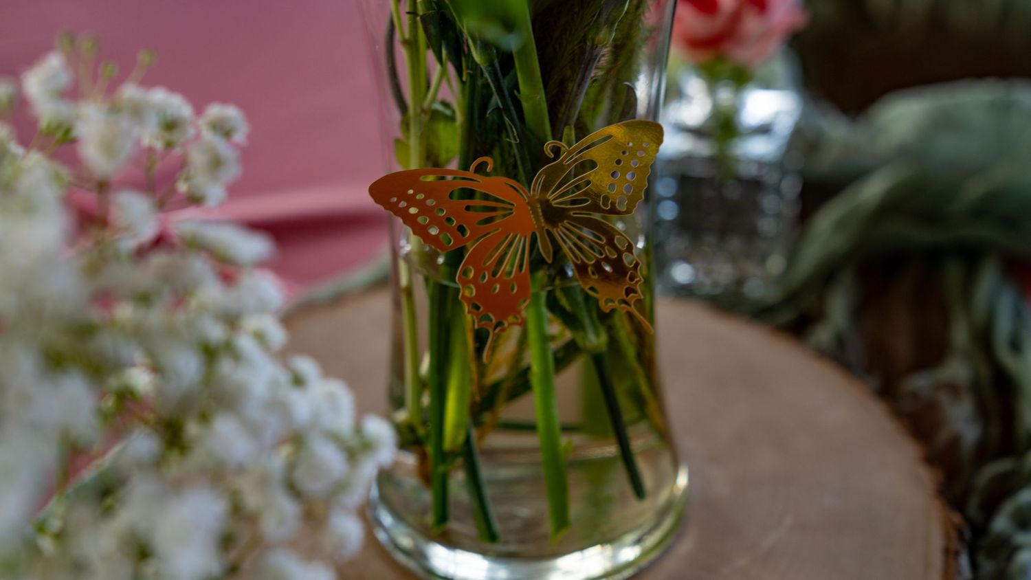 Orange butterfly decoration on flower stems in glass vase.