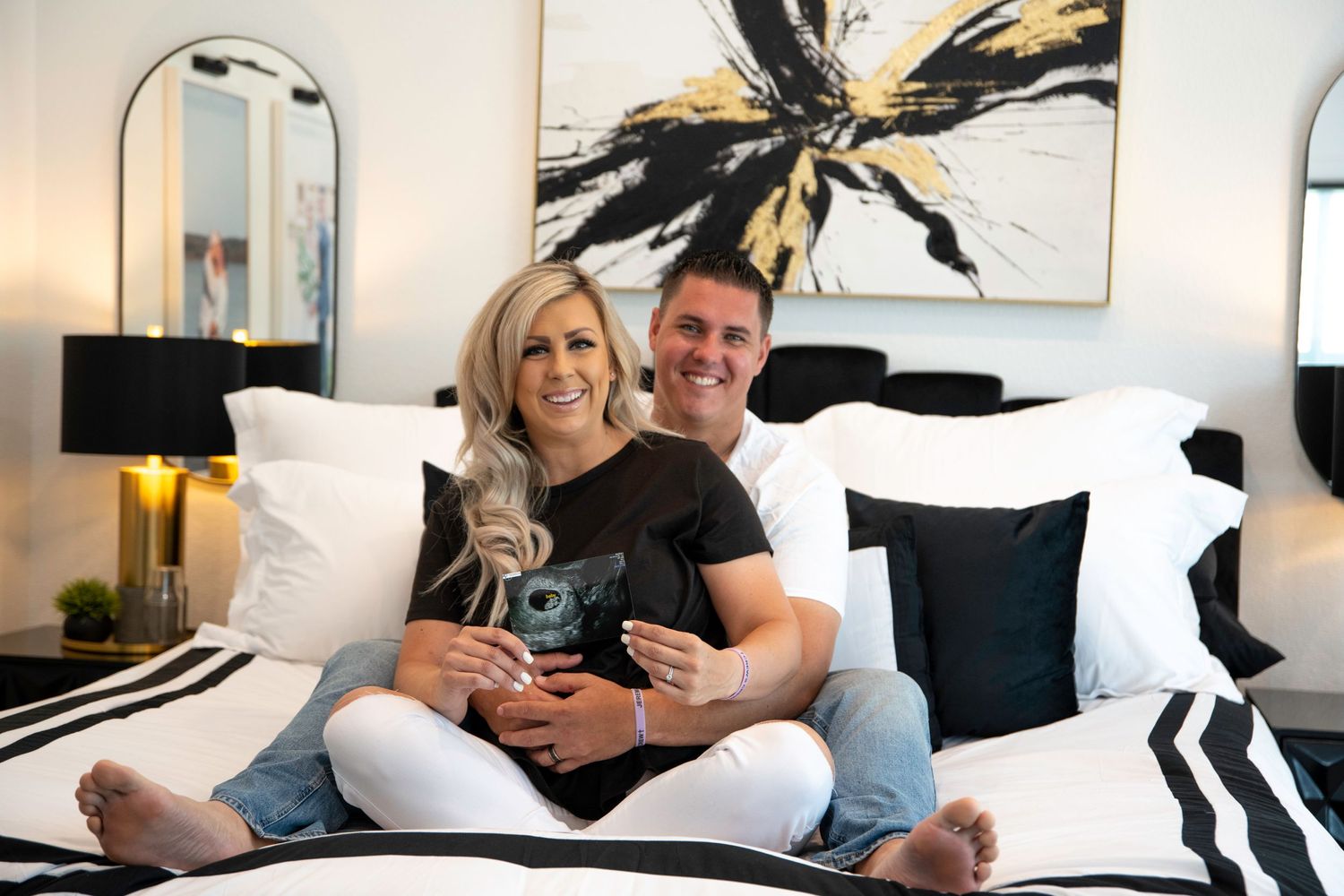 Couple relaxing on bed with black and white decor and modern artwork.