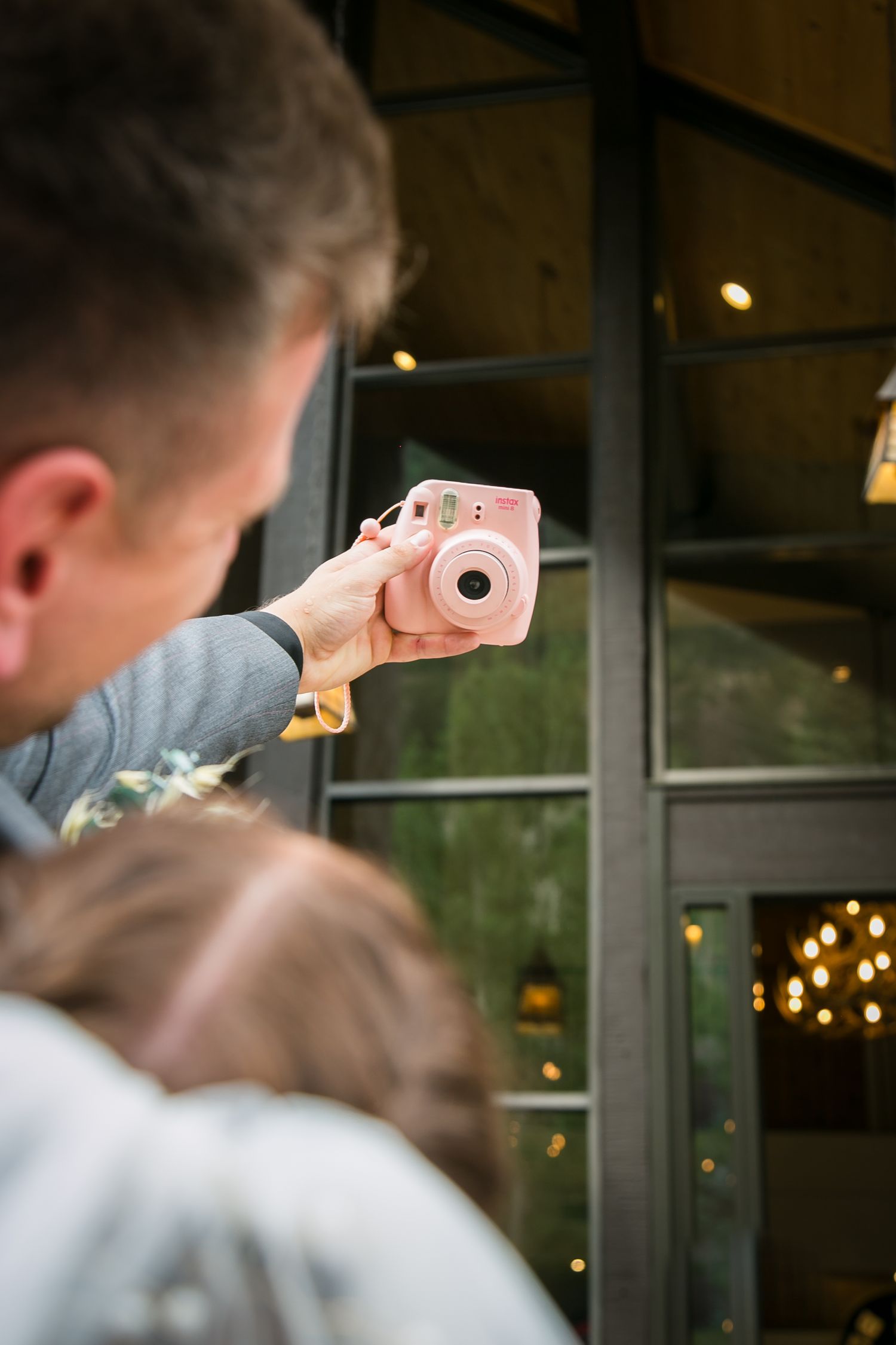 Someone holds a pink Instax camera while taking photos at an indoor event.