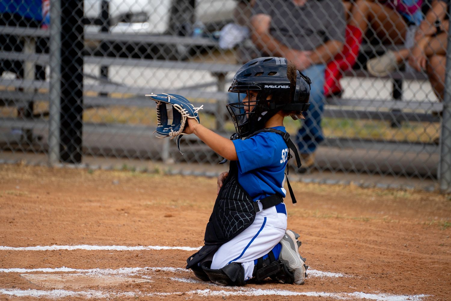 A baseball player wearing a blue and white uniform slides safely into home plate during a game.