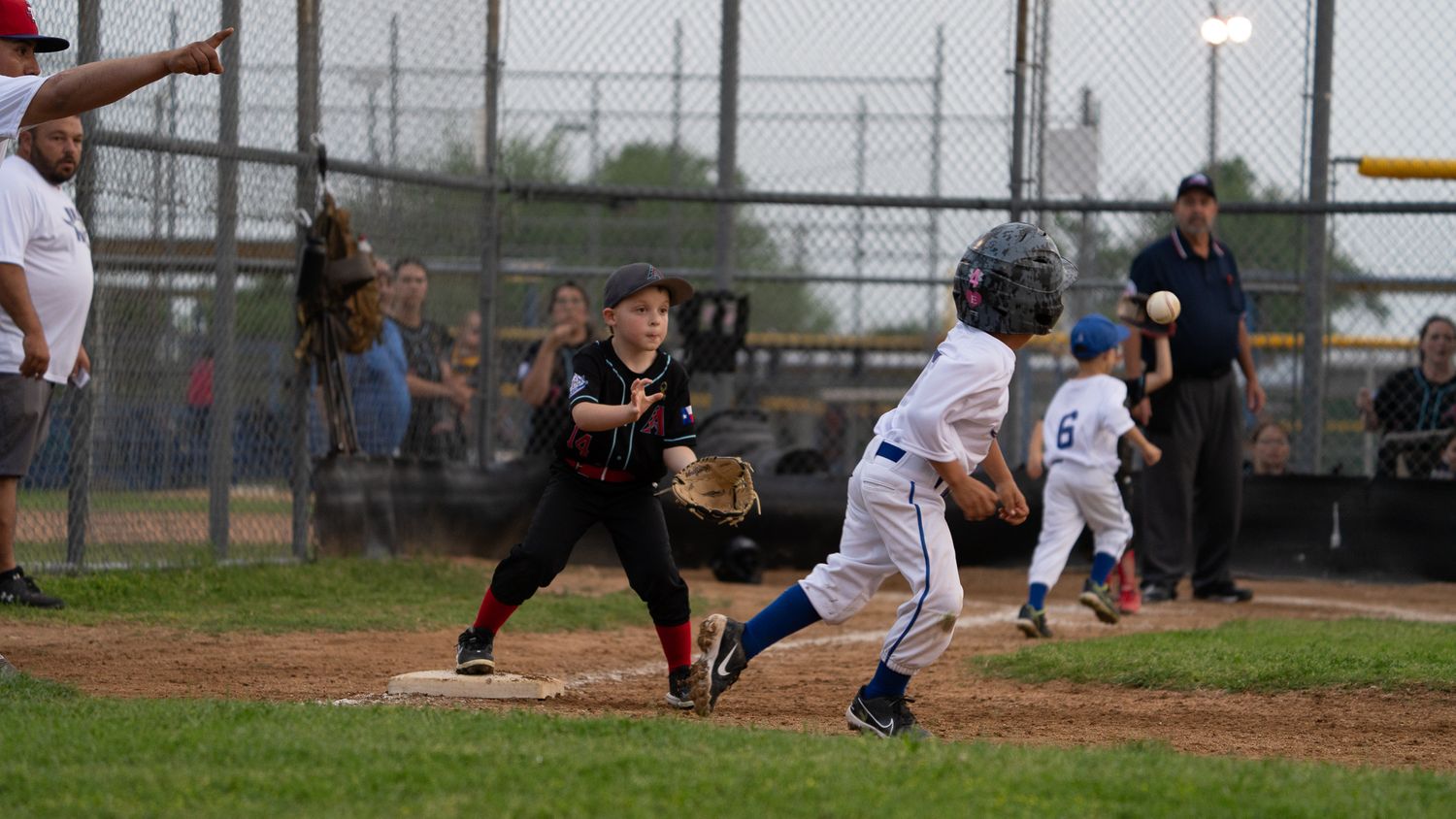 Baseball player in dark uniform swings at pitch during game while catcher and umpire observe from behind plate.
