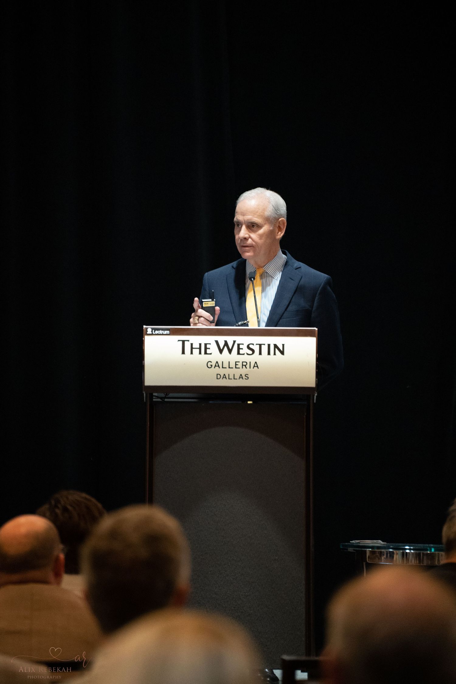 Speaker delivering presentation from podium at The Westin Galleria conference.