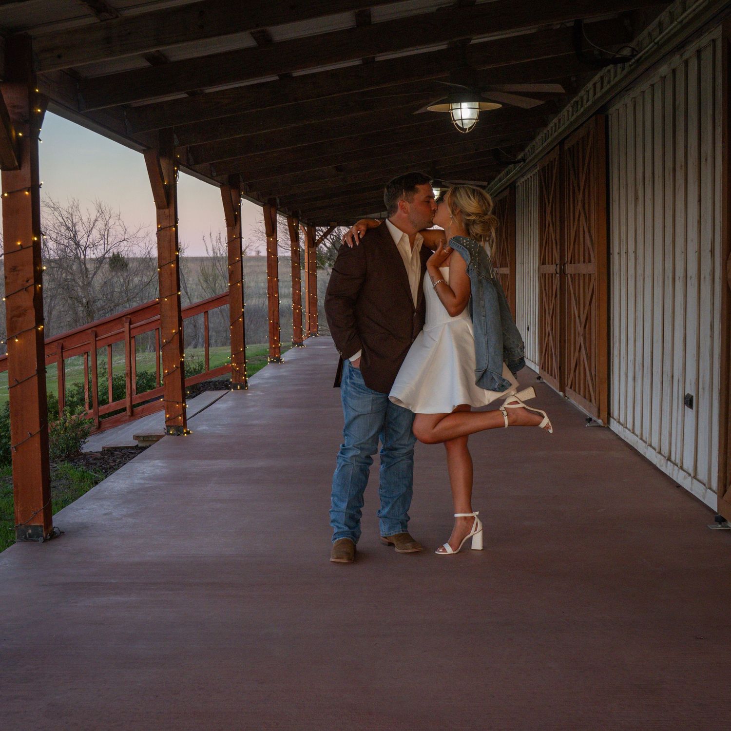 A romantic moment on a rustic porch with wooden beams and railings at sunset, overlooking an autumn landscape.