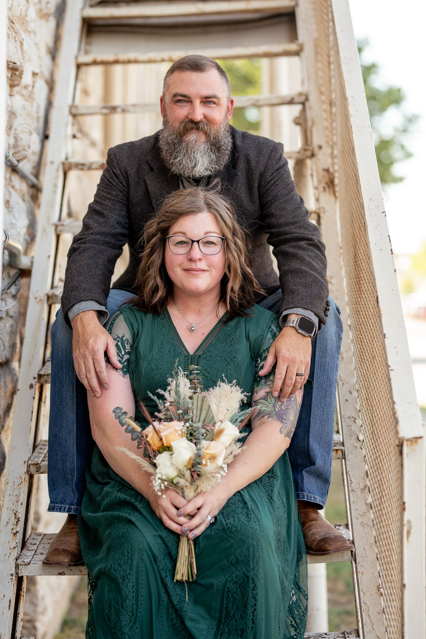 A rustic engagement photo on vintage wooden stairs with a floral bouquet.