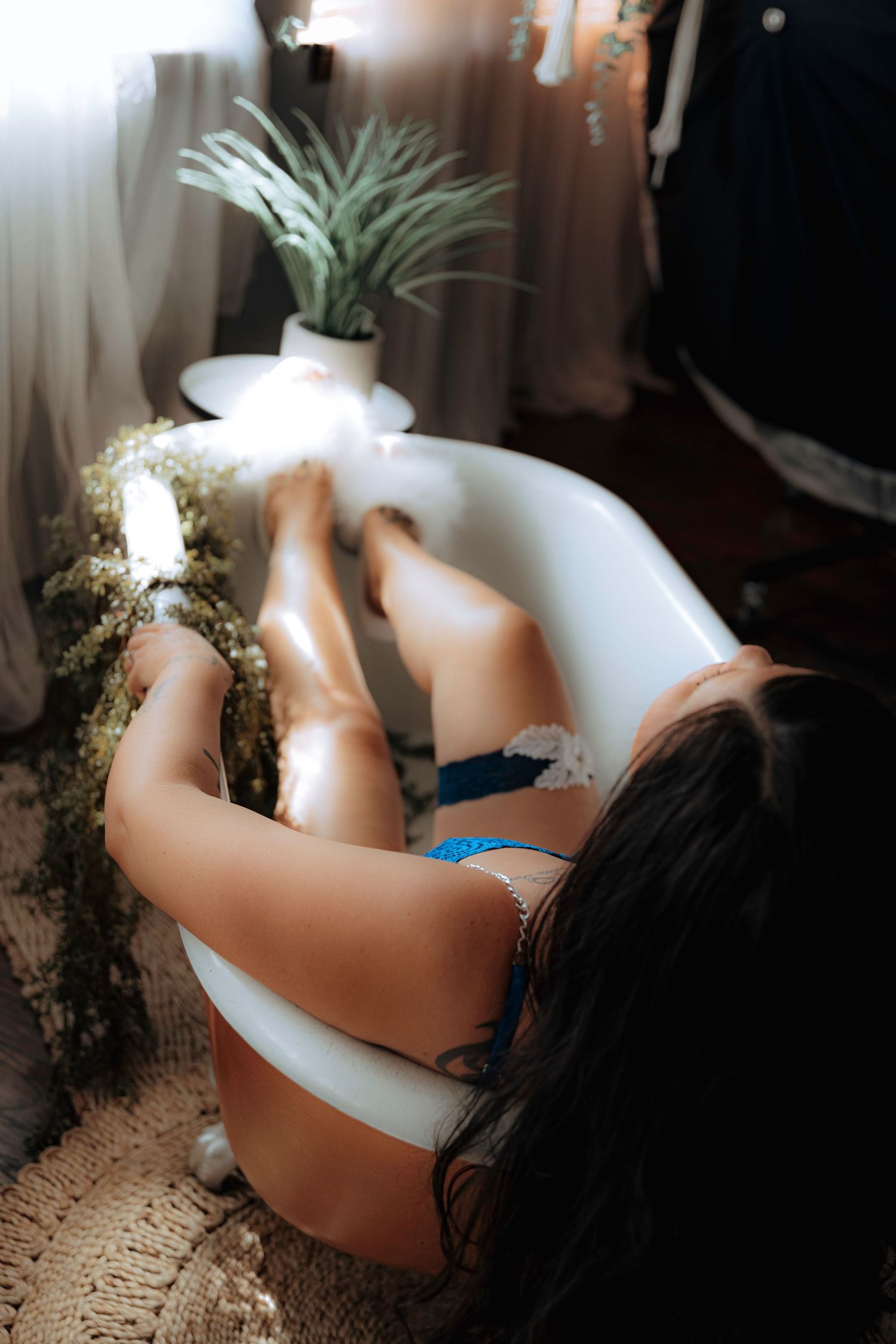Atmospheric bathtub photography with soft lighting and air plants in the background.