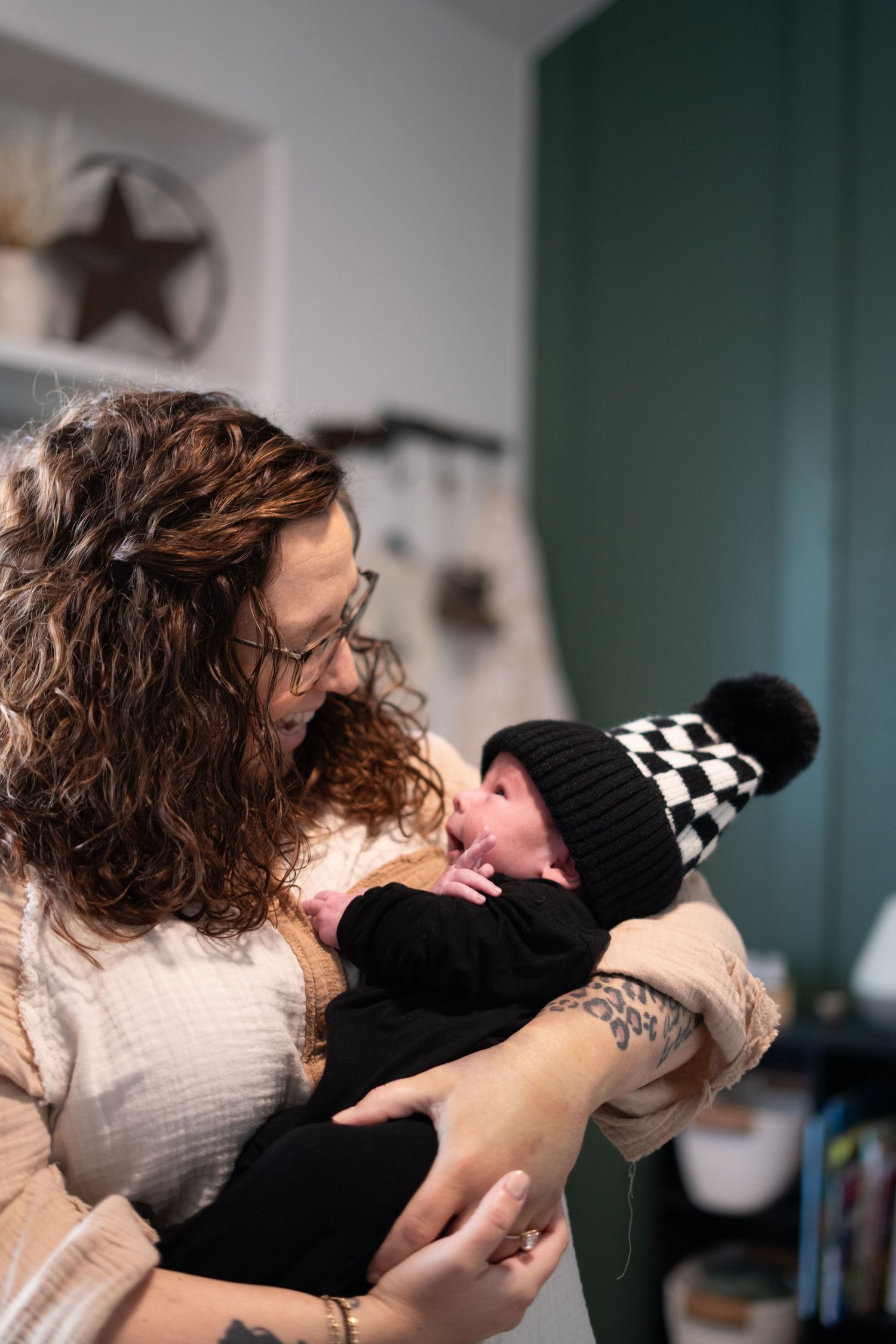 An intimate family moment with a baby wearing a pom pom beanie indoors.