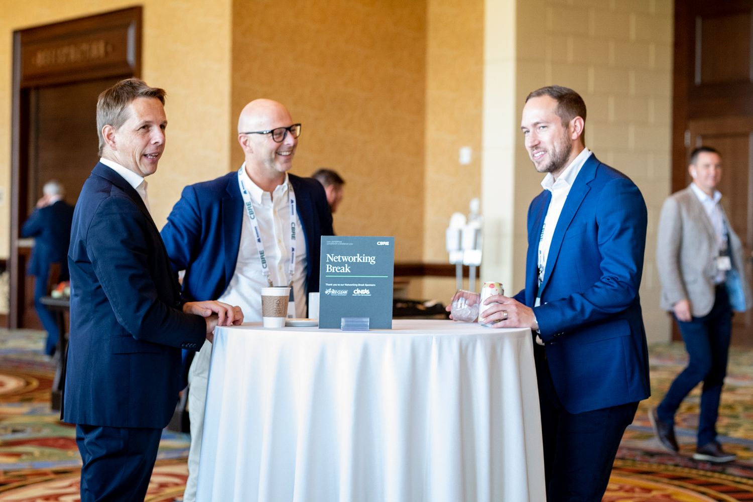 Business professionals having a discussion around a cocktail table at a networking event.