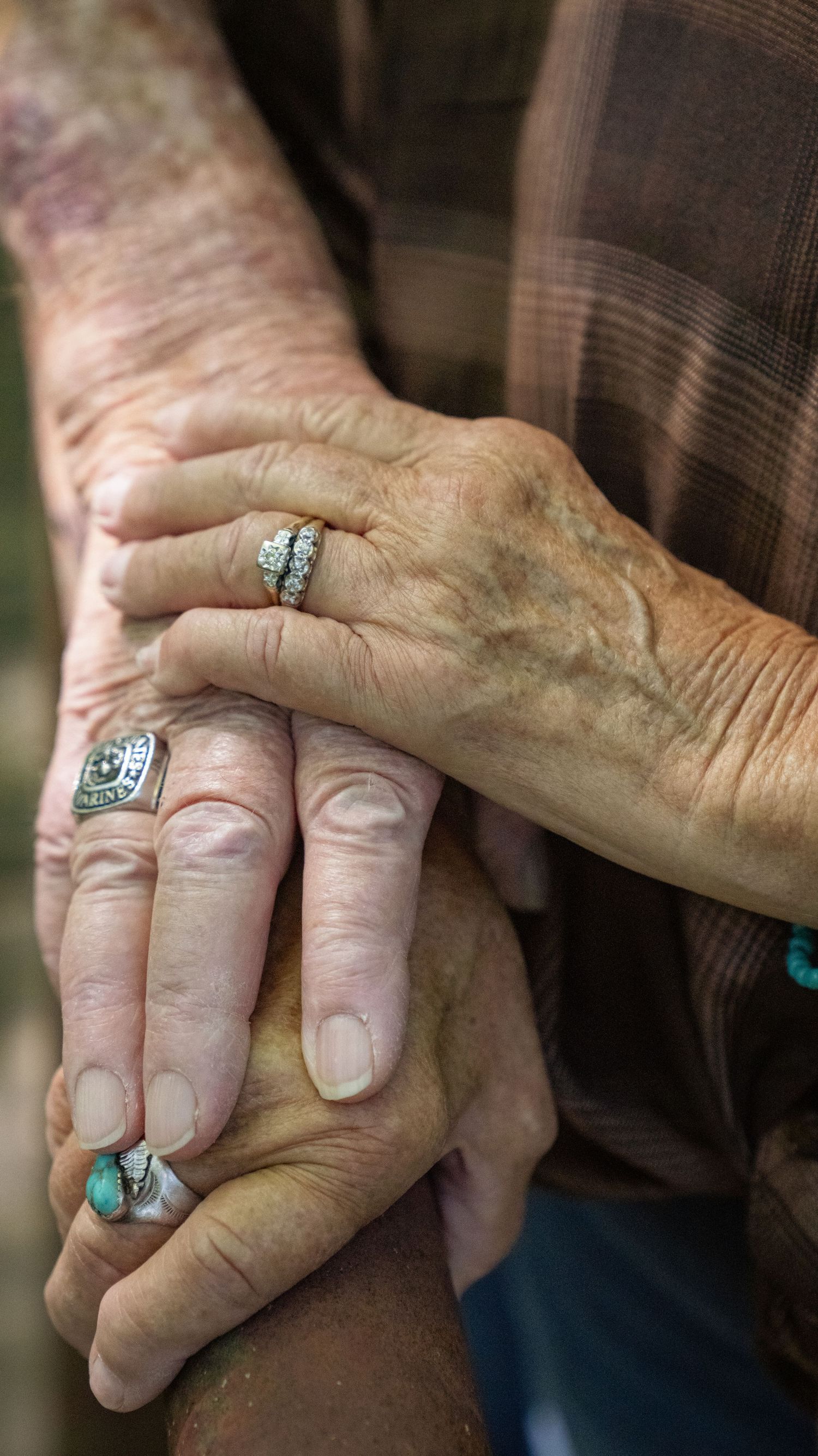 Close-up of weathered hands with rings touching in an intimate gesture of affection.