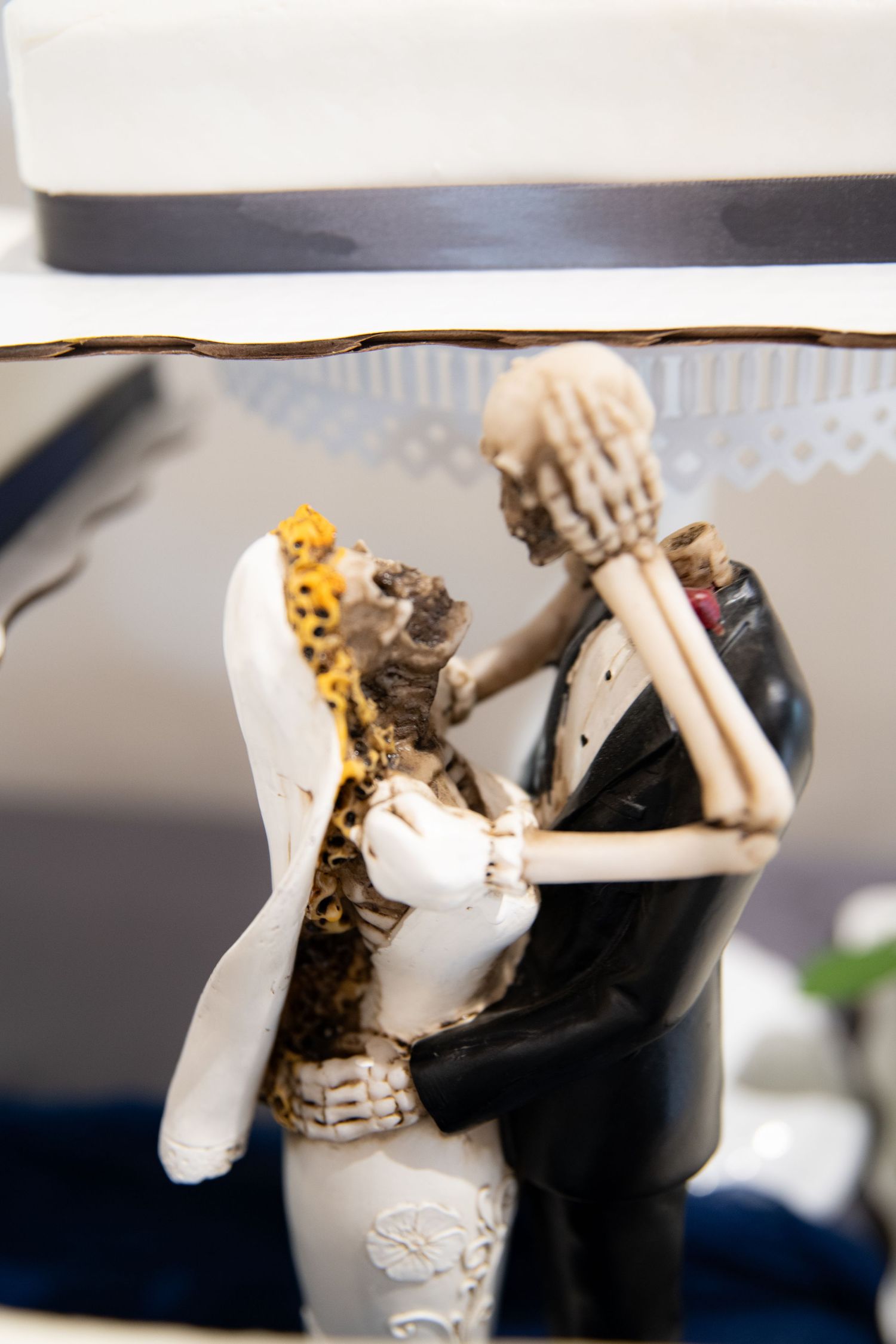 Wedding cake topper featuring a bride and groom figurine in black and white formal attire.