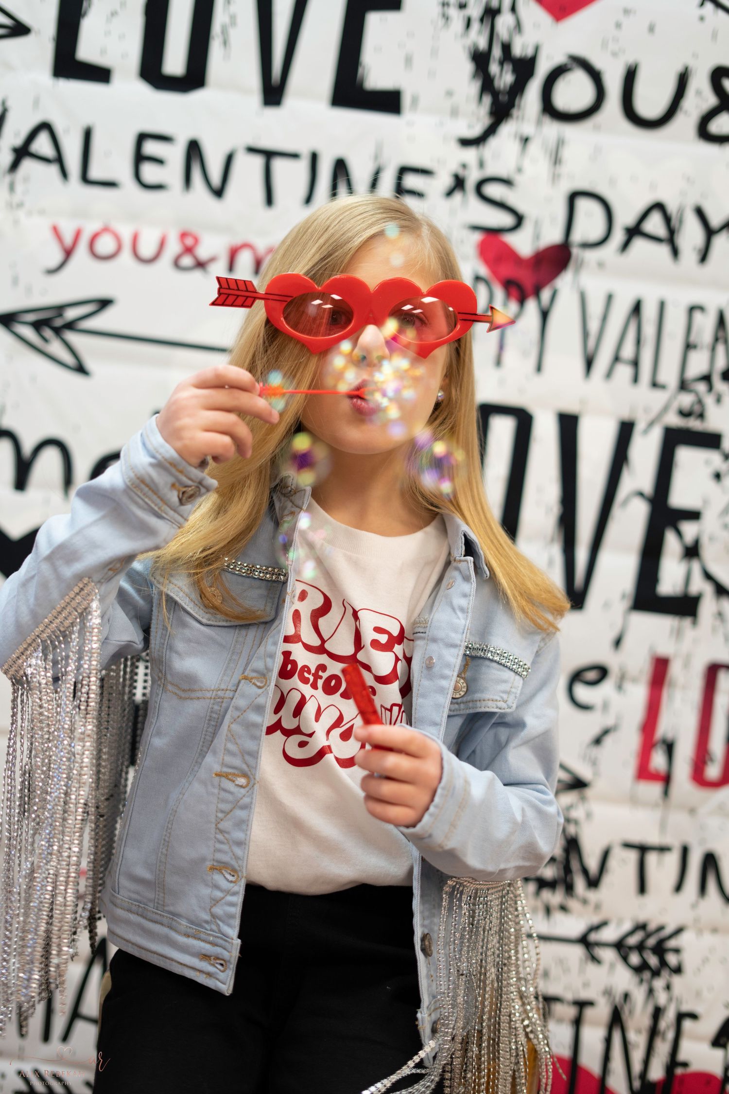 Valentine's Day themed photo with denim jacket and heart decorations against graffiti wall.