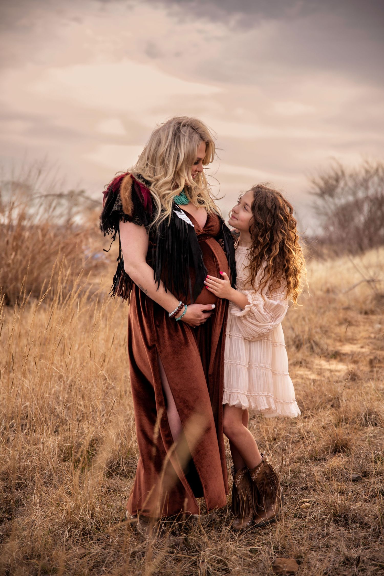 Mother and daughter sharing tender moment in field during golden hour sunset.