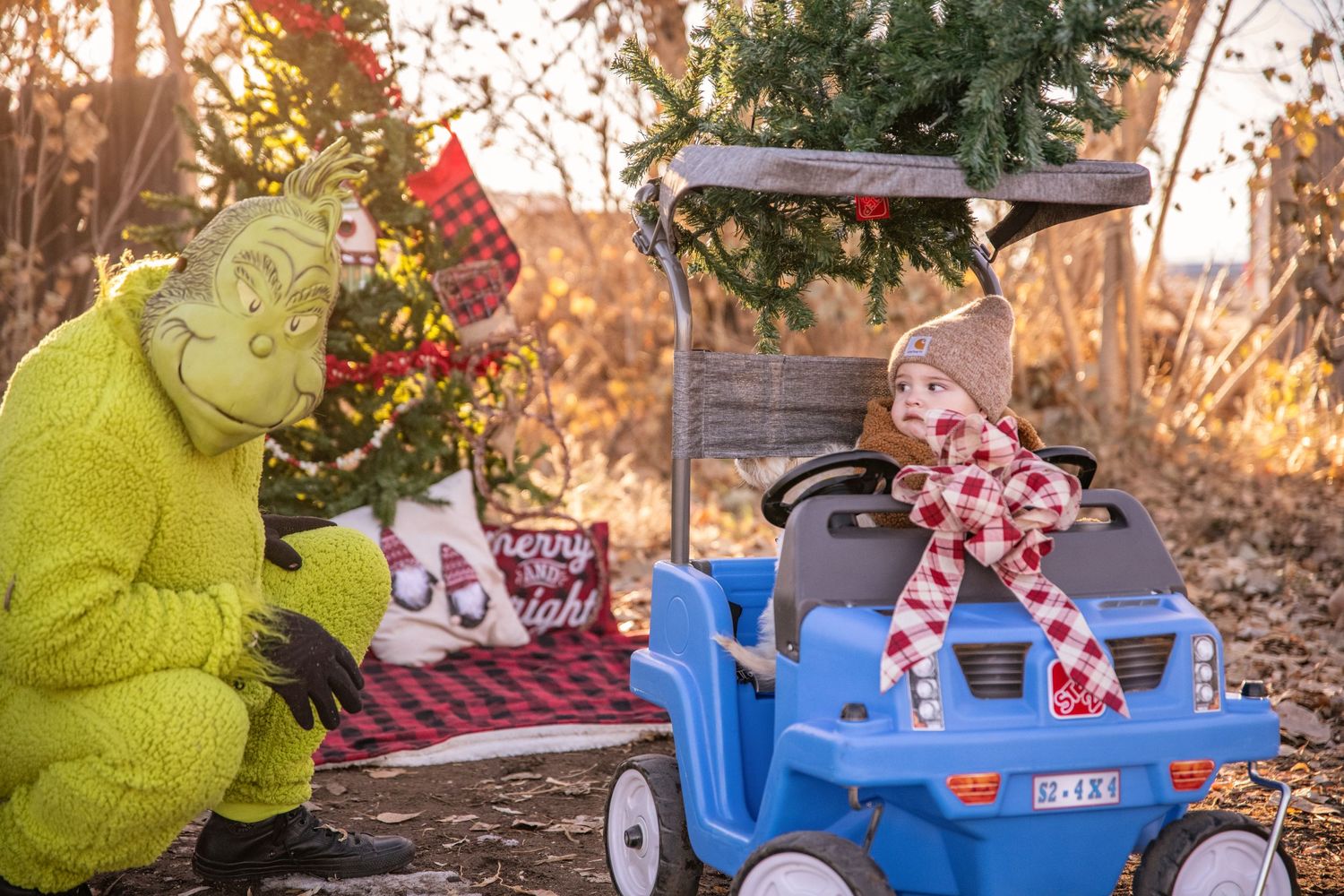 A whimsical holiday scene with a blue toy car and green Grinch decoration against a golden sunset.