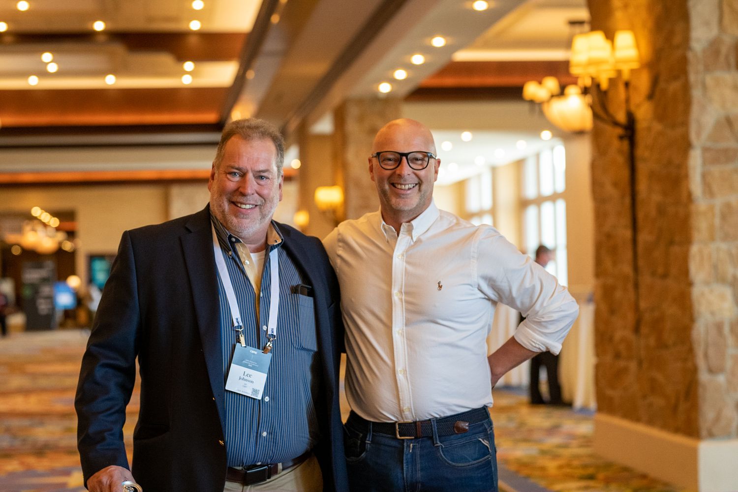 Conference attendees in business attire networking at a professional event.