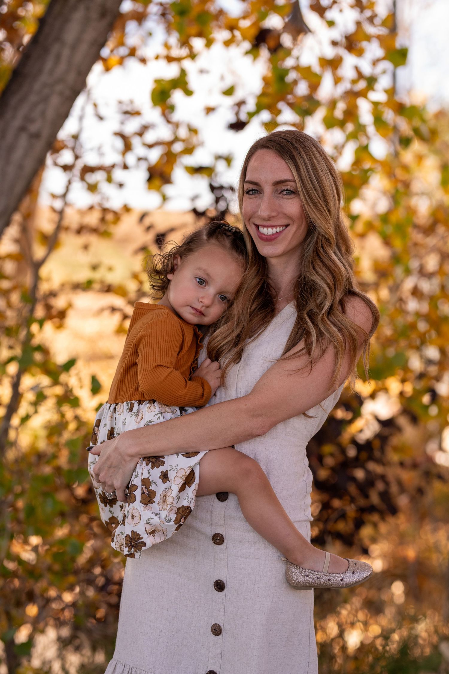 An autumn portrait in golden light showing a warm embrace against fall foliage.