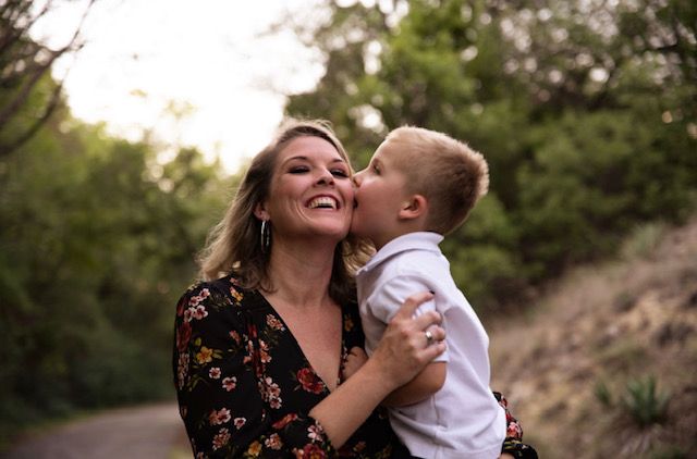 Mother and child sharing joyful moment outdoors at sunset.