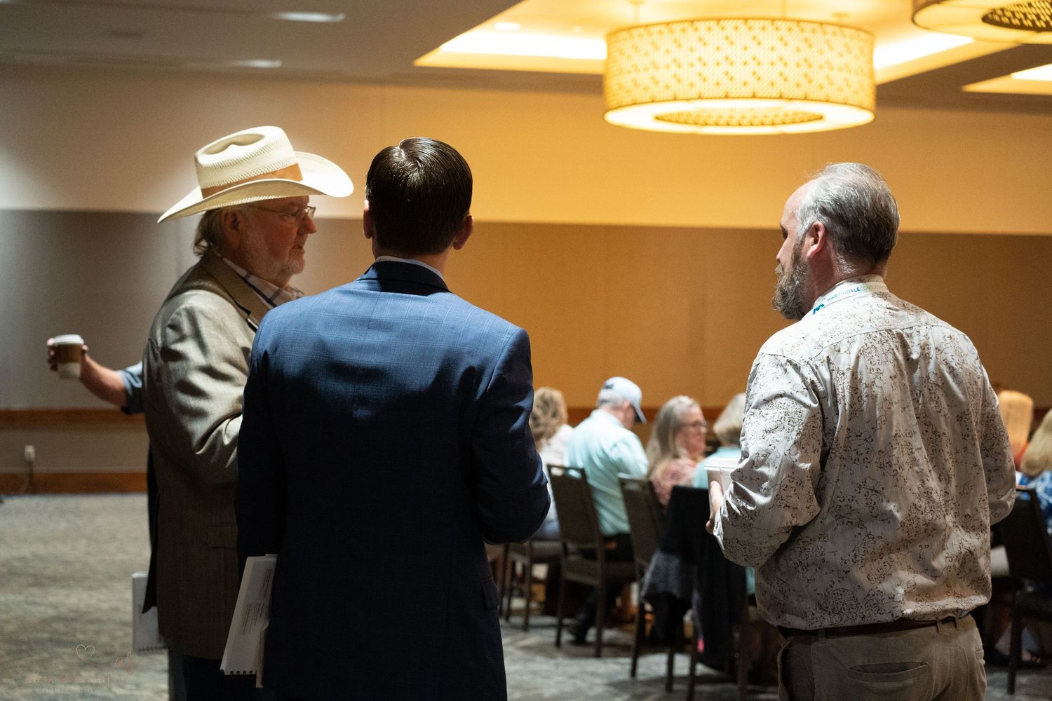 Three attendees engaged in conversation during conference networking session.