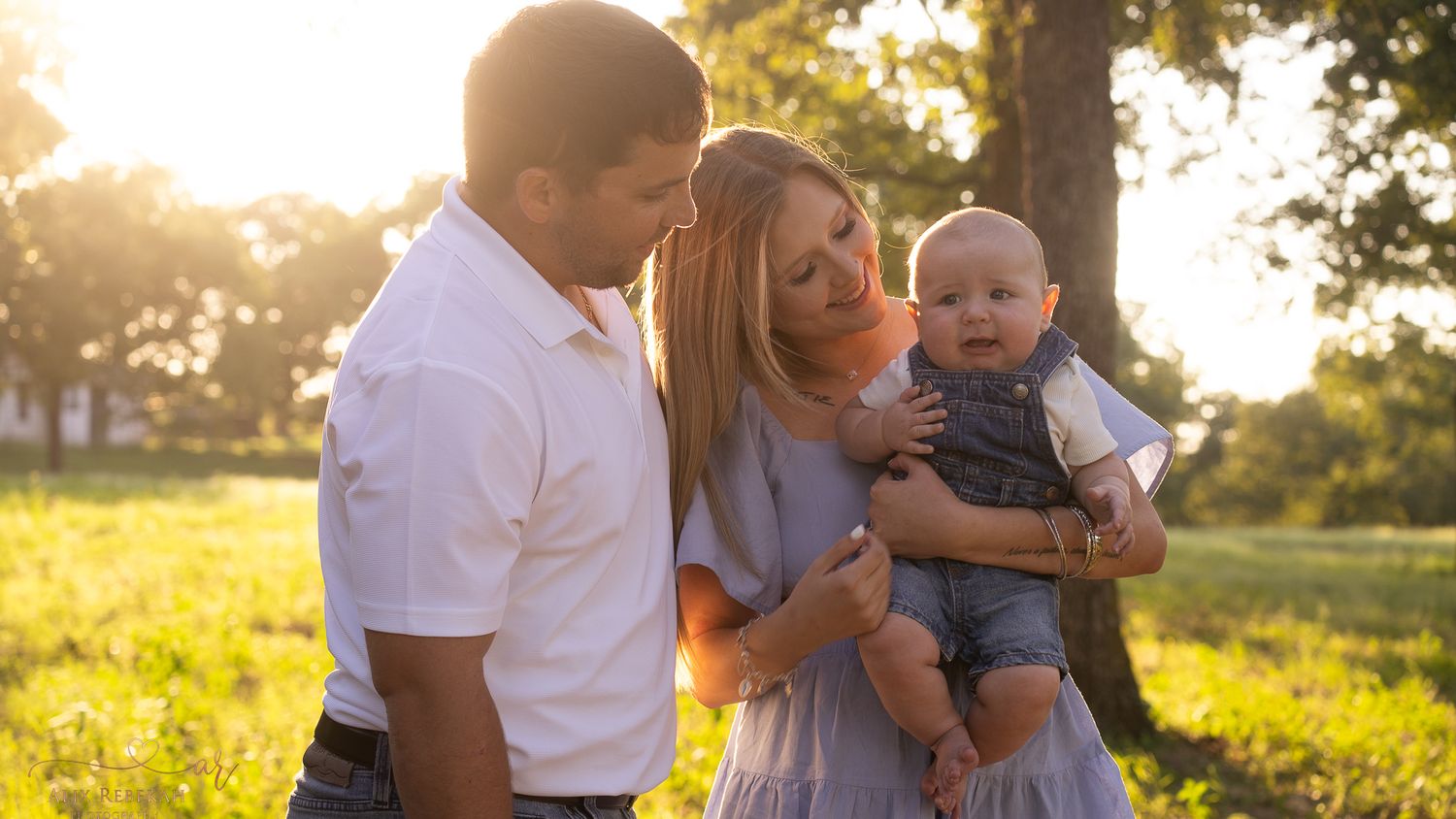 A tender family moment captured in a sun-drenched meadow at golden hour.