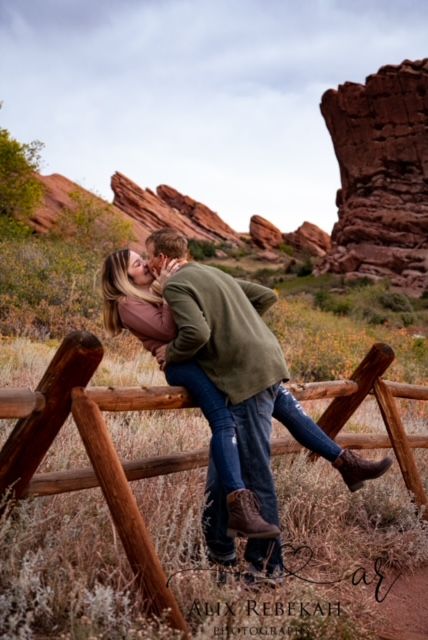 Romantic couple embracing at Red Rocks Park with dramatic rock formations in background.
