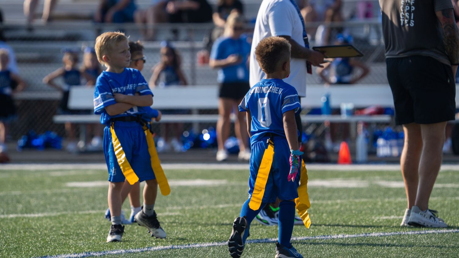 Youth football players participating in practice drills on an outdoor sports field.