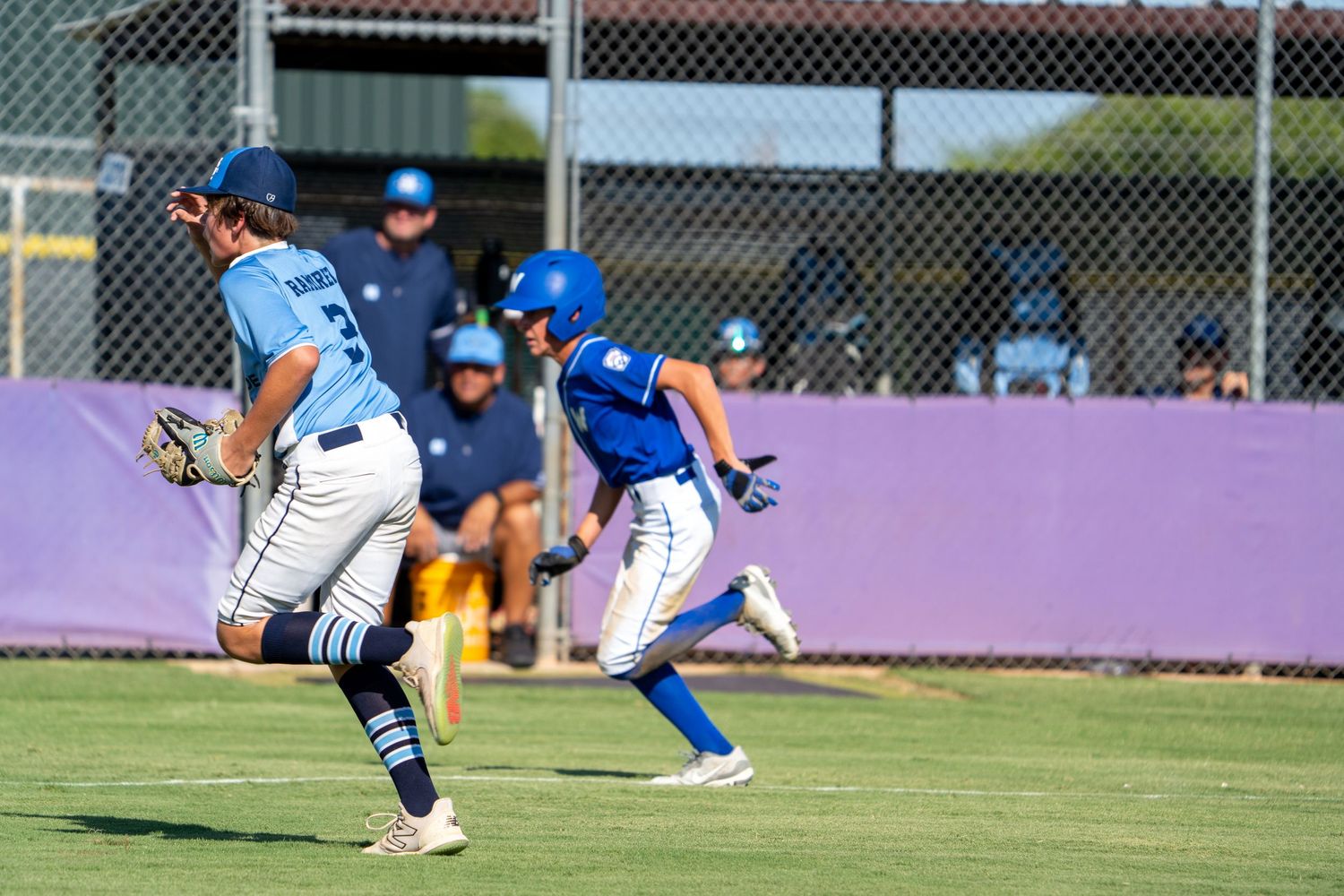 Baseball player sliding into base during game while defender attempts to make the tag at field.