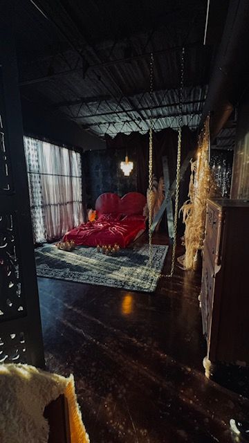 Dramatic bedroom with suspended red bed and hanging lights creating a romantic atmosphere.