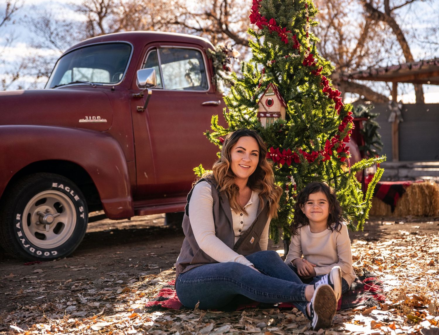 Holiday portrait session with vintage red truck featuring decorated Christmas tree.