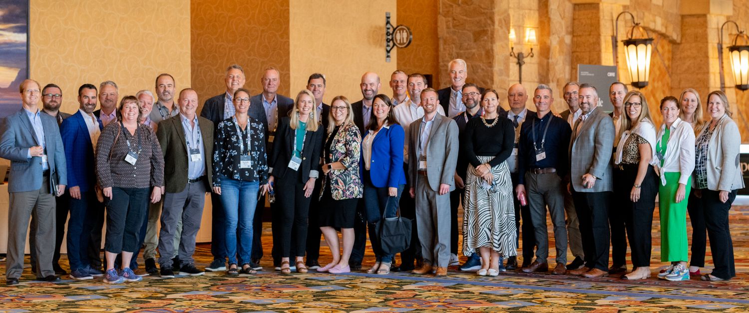 Large group photo of conference attendees gathered in a hotel conference space.