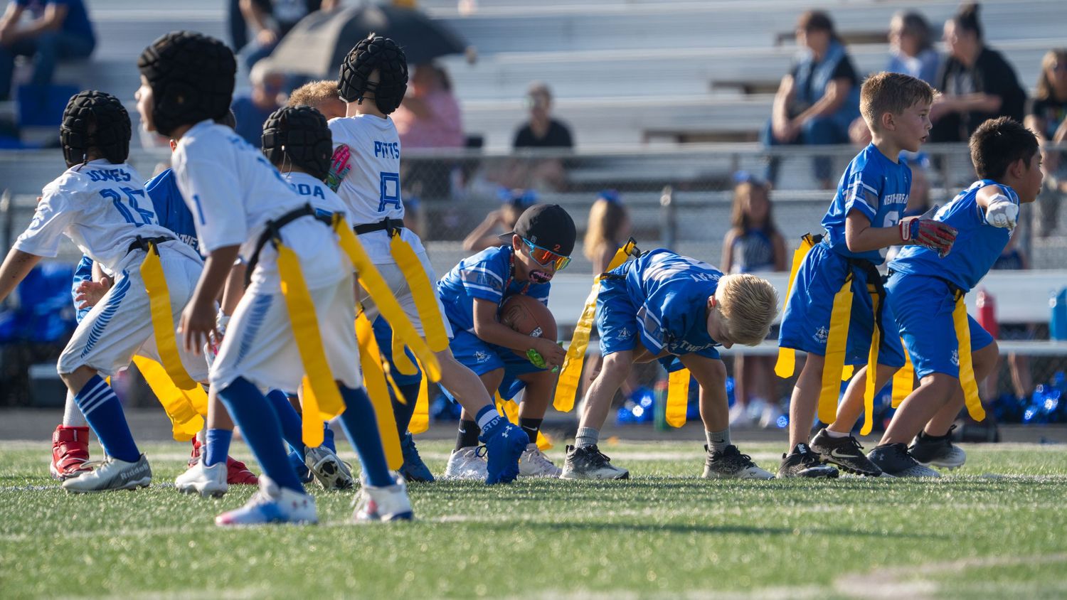 Young football players in blue and yellow uniforms line up in formation during a game.
