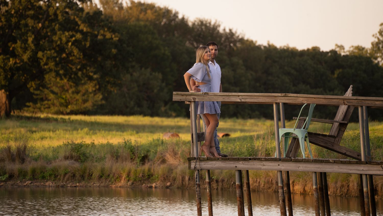 A tranquil sunset scene of a wooden dock extending over a peaceful pond surrounded by trees.