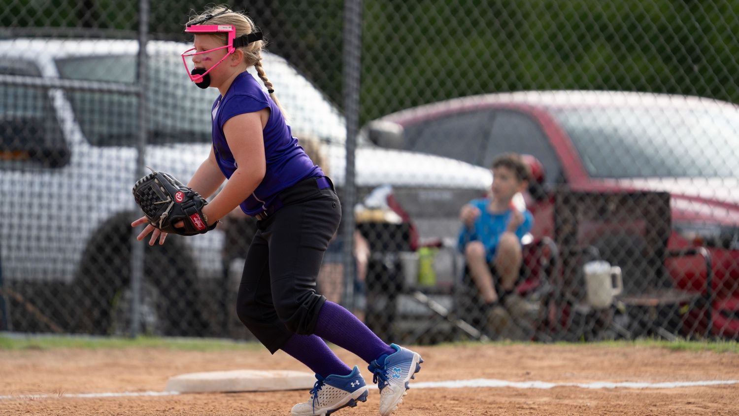Softball player in purple uniform stands ready in batting position on field during game.