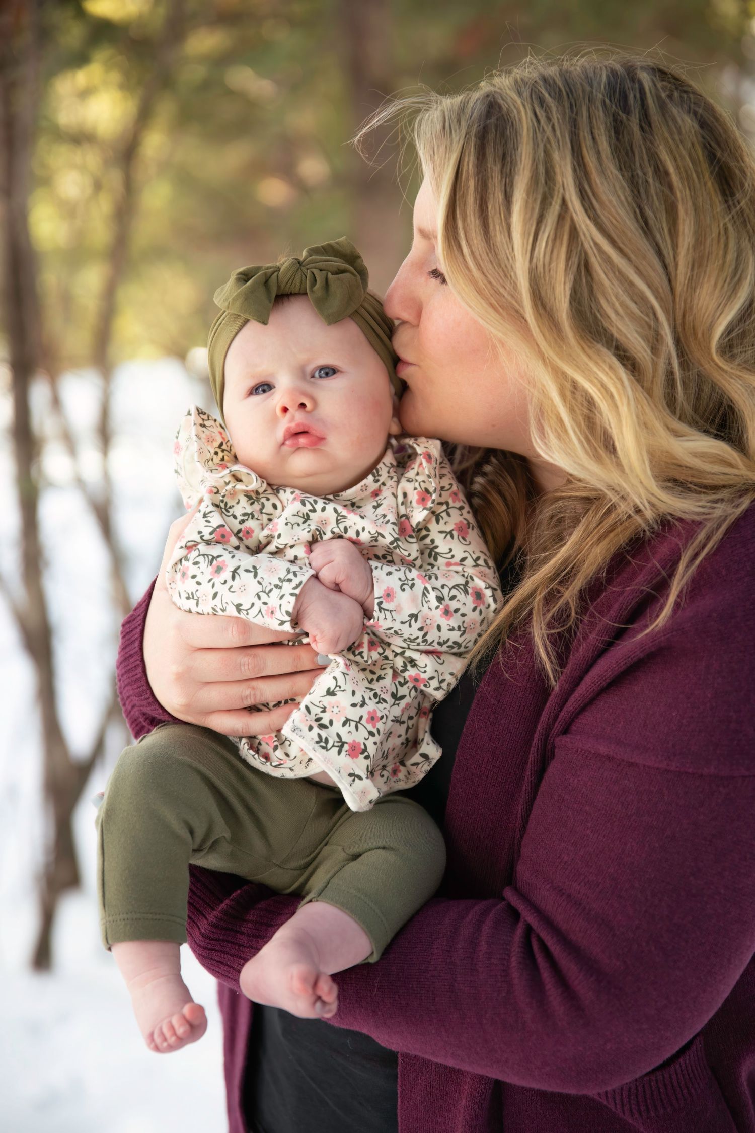 A tender moment between parent and baby in winter outdoor setting.