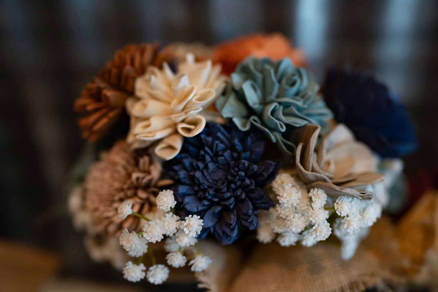 A delicate arrangement of blue, beige, and brown fabric flowers with baby's breath.