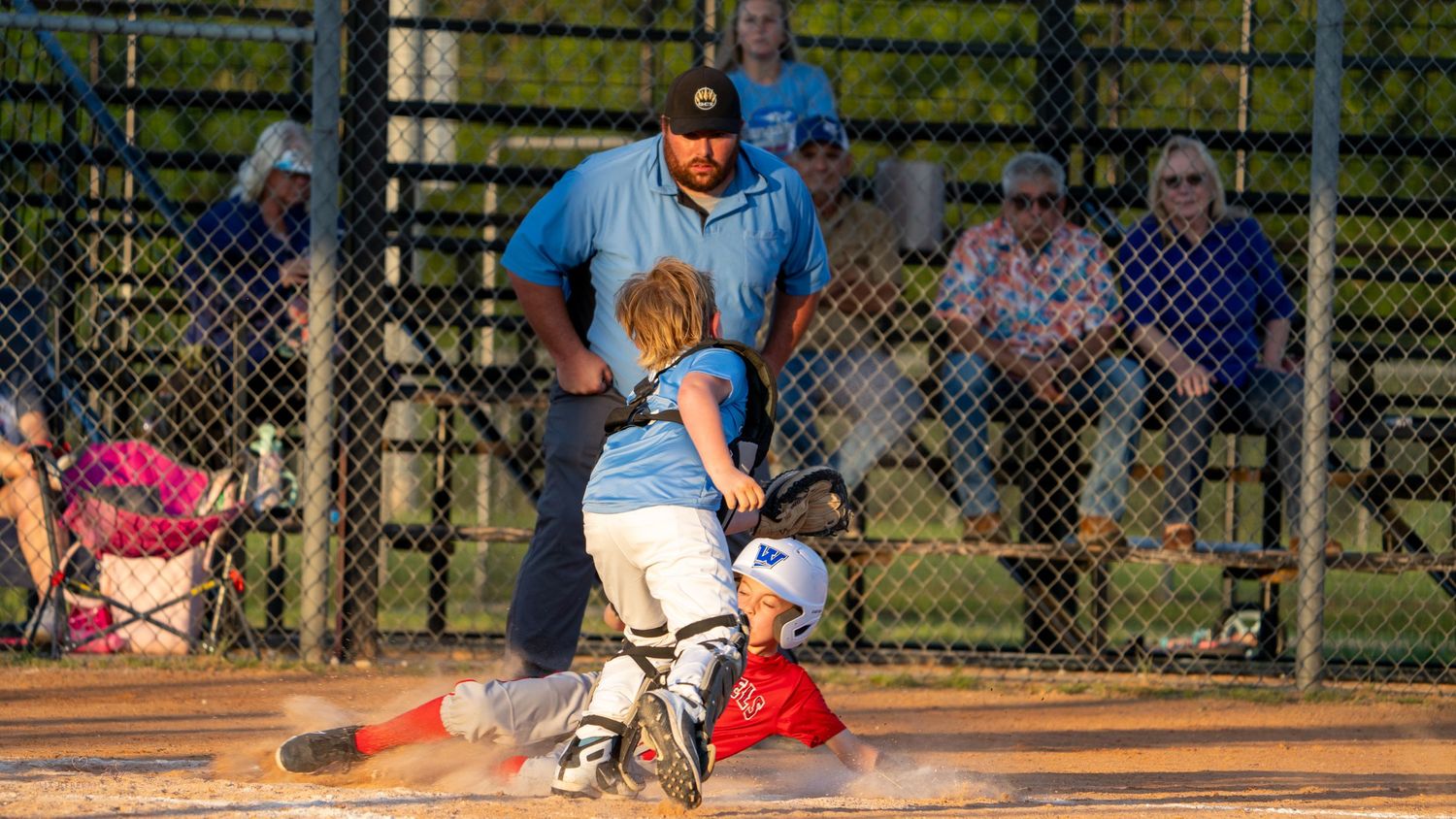 Youth baseball players in action during a game, showing batting, fielding and sliding plays on a sunny day.