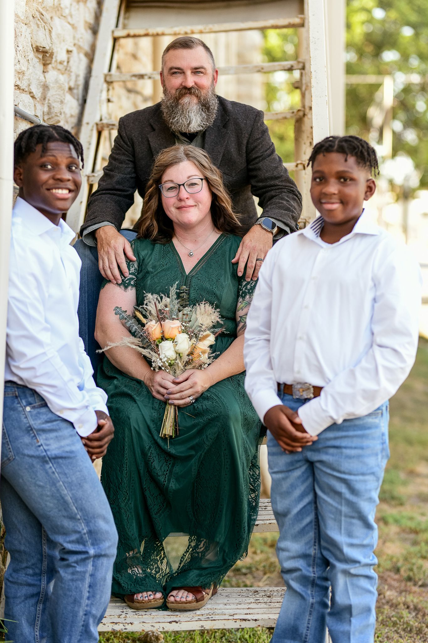 Group photo on outdoor steps with green dress and bouquet.