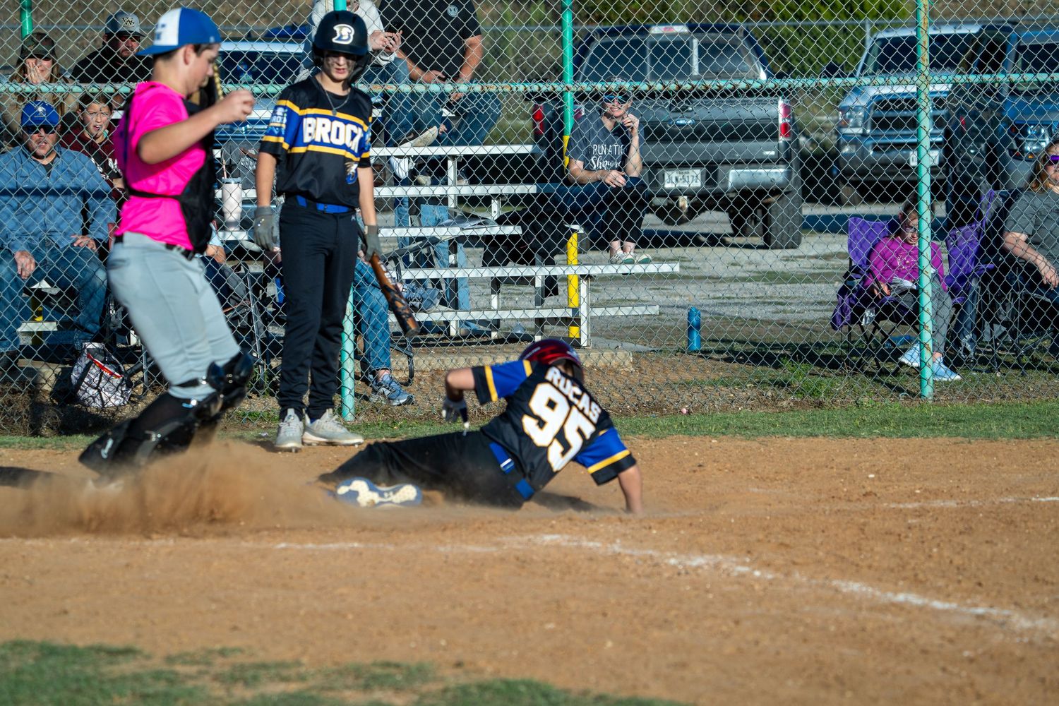 Softball player in a pink shirt swings the bat at home plate during a game.