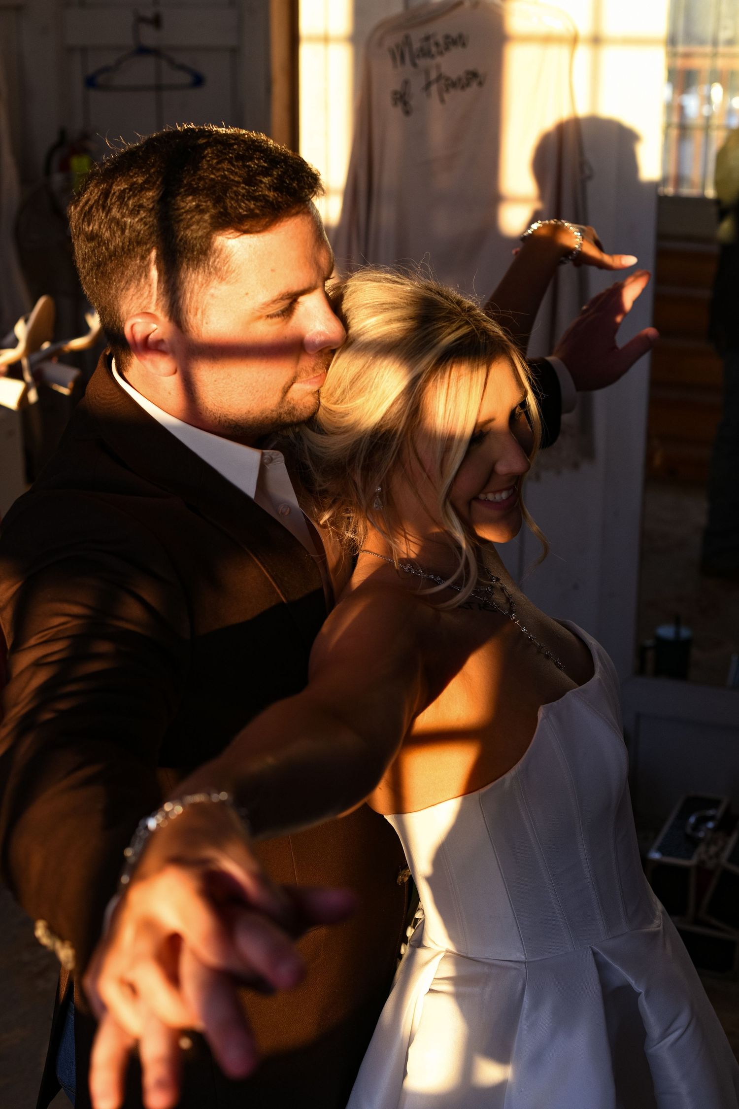 Two people share an intimate moment in dramatic side lighting while leaning against a wall.