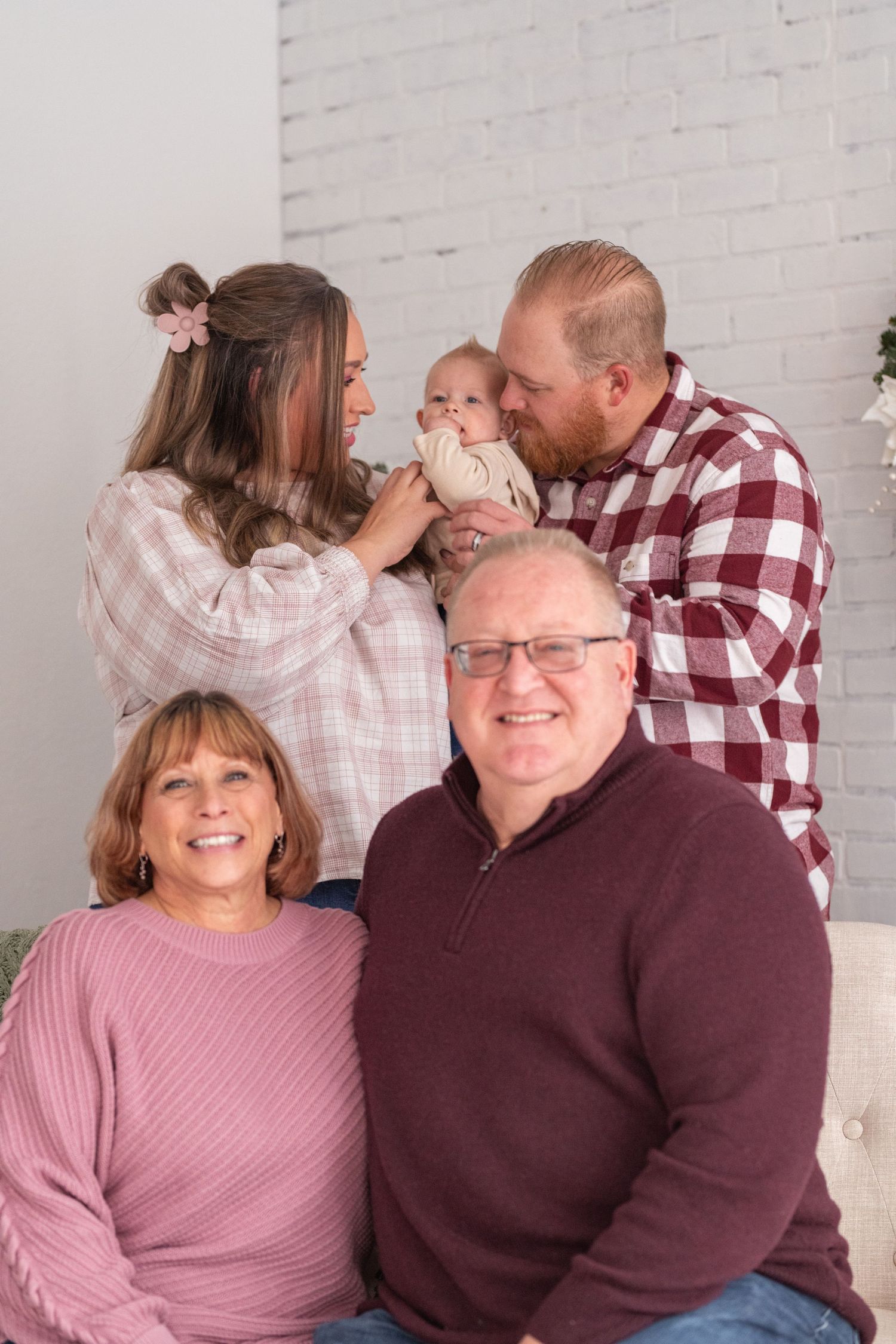 A couple in matching burgundy and pink outfits share affectionate moments in a series of photos against a white brick wall.