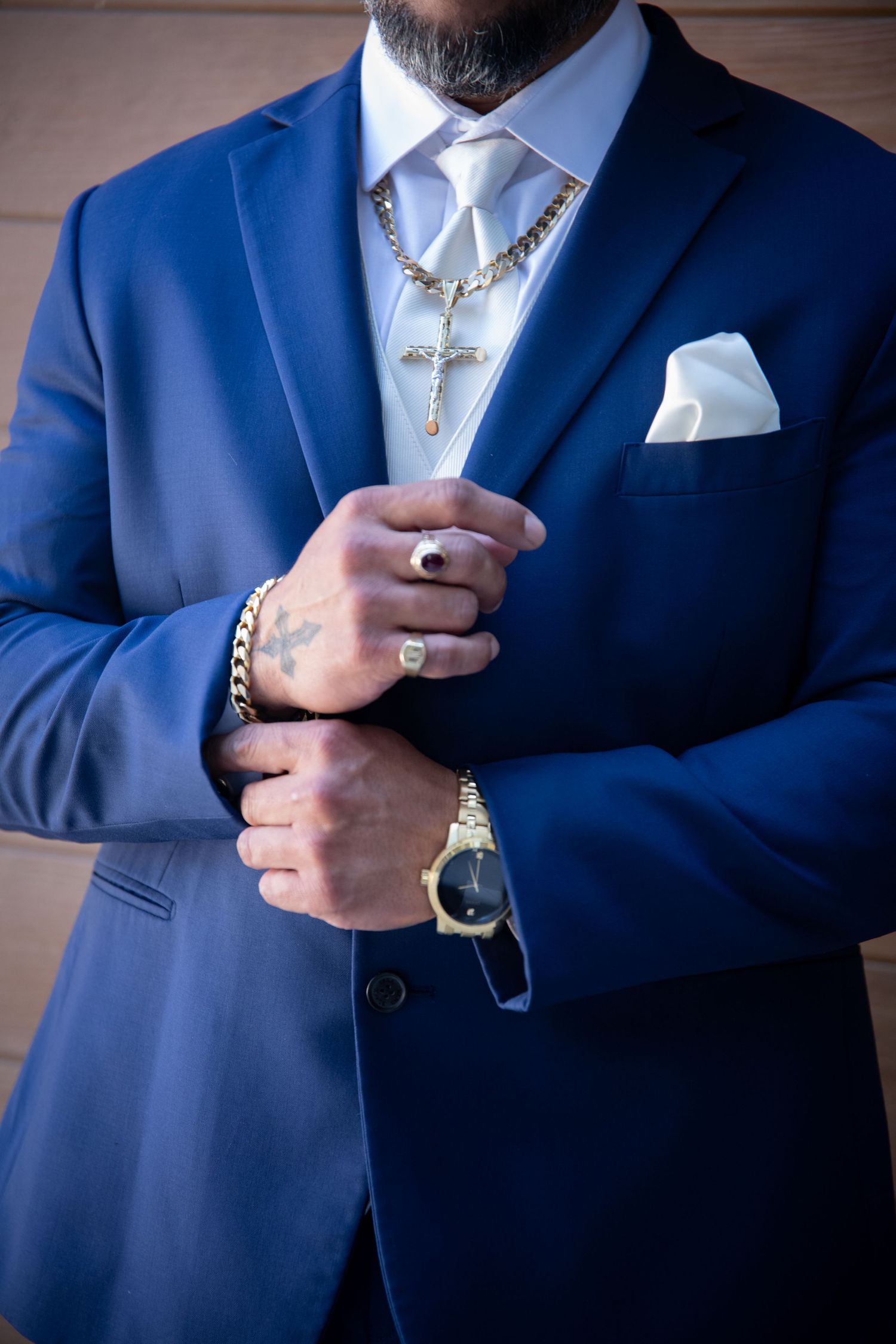 Close-up of blue suit with silver crucifix necklace and white pocket square.