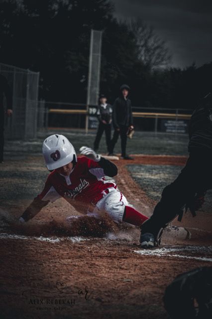 Baseball player sliding into home base creating a cloud of dirt during an intense play at the plate.