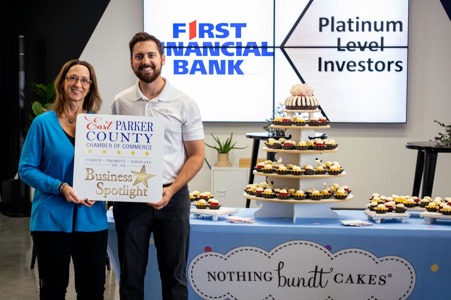 Two business professionals display award certificate in front of dessert display at First Financial Bank event.