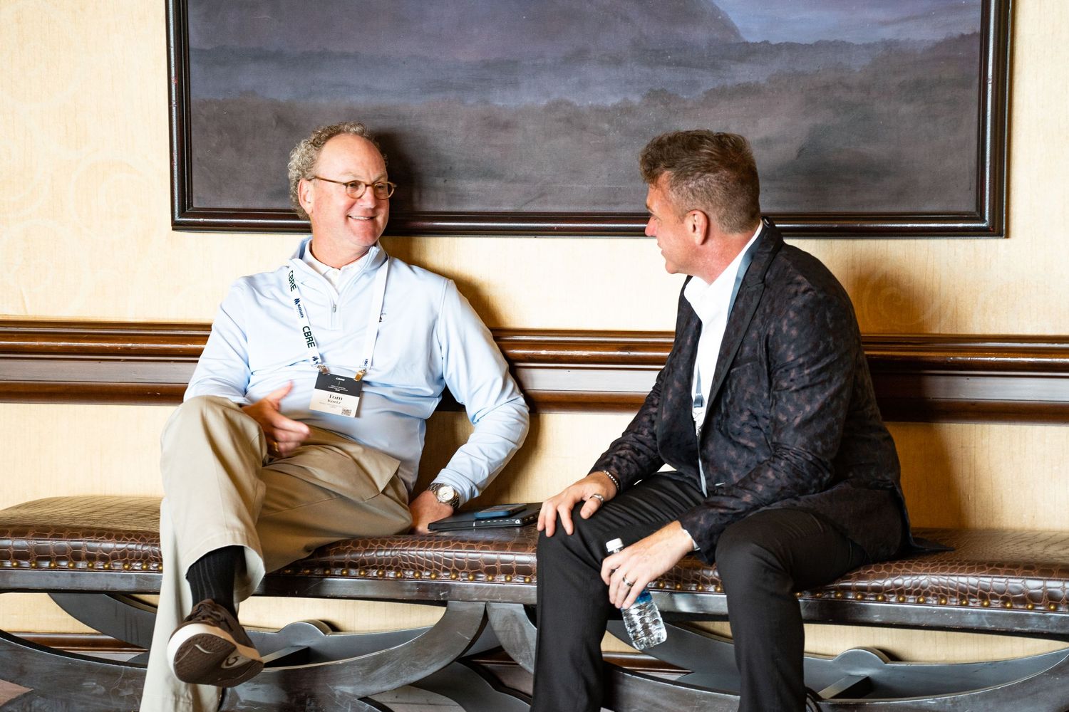 Two professionals having casual conversation in business lounge setting.