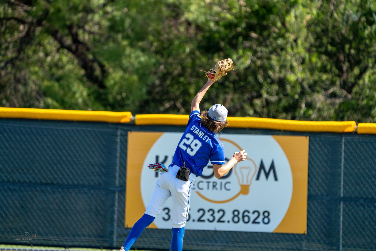 Baseball player wearing blue jersey takes a swing at home plate during competitive game.
